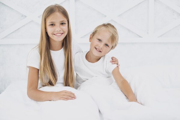 siblings-staying-bed-while-looking-camera